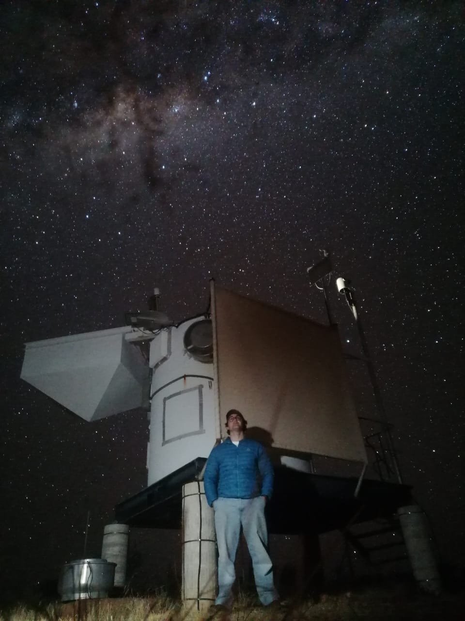 Enzo standing in front of the ROTSE-IIIc enclosure at night, with the Milky Way overhead